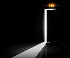 an open door with the exit light shining down on it in a dark room that appears to be dimly lit