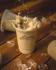 a cup filled with ice cream on top of a wooden table