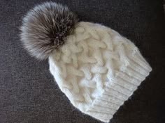 a white knitted hat with a fur pom