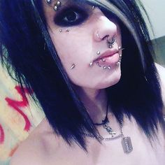 a woman with black hair and piercings on her face is posing for the camera