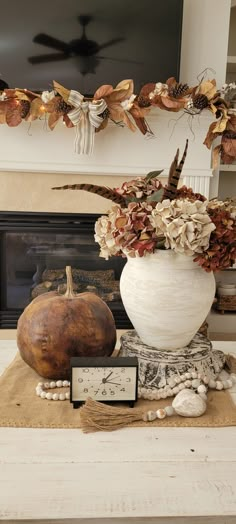 a white vase filled with flowers sitting on top of a wooden table next to a clock