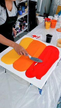 a woman in an apron is cutting up a piece of art on a white table