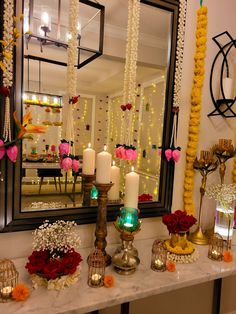 a table topped with lots of candles and flowers next to a mirror covered in lights