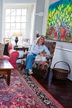 a woman sitting in a living room next to a red couch