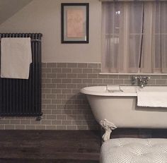 an old fashioned bathtub in the corner of a bathroom with exposed brick walls and wooden flooring