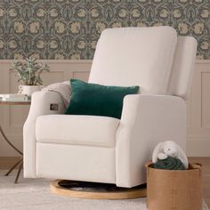 a white rocking chair in front of a wallpapered room with green and gold accents