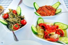 three bowls filled with different types of food on top of a white table covered in blue and white checkered cloth