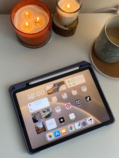 an ipad sitting on a table next to some candles