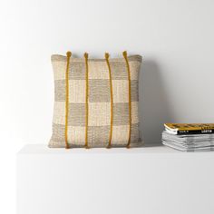 a pillow sitting on top of a white shelf next to a stack of books and magazines