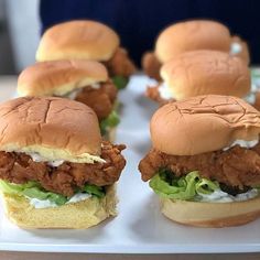 several chicken sandwiches sitting on top of a white plate