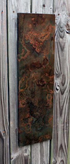 an old rusted metal plate on a wooden fence with peeling paint and holes in it