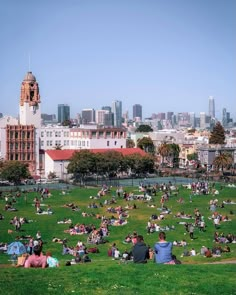 many people are sitting on the grass in a city park