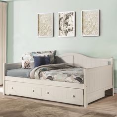 a white daybed with drawers underneath it in a room that has blue walls and hardwood floors