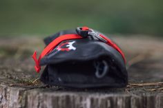 a small black bag with red straps sitting on top of a tree stump