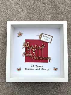 a white frame with a red and gold 50th birthday card in it on the floor