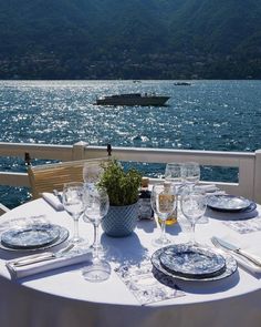 the table is set for two on the balcony overlooking the water and boats in the distance