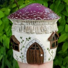 a close up of a hand holding a small toy house with a purple roof and door