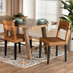 a dining room table with two chairs and a potted plant