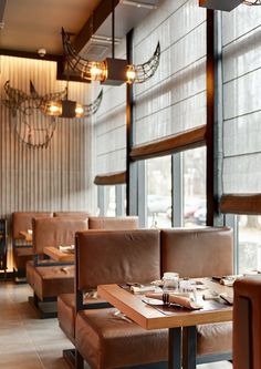 an empty restaurant with brown leather booths and wooden tables in front of large windows that look out onto the street