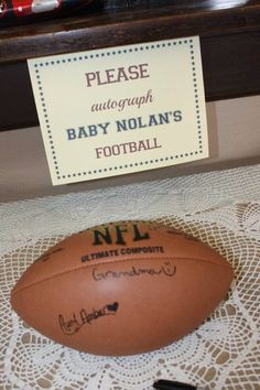 a football sitting on top of a table next to a sign that reads please autograph baby nolan's football