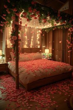 a bed with rose petals on it and lights in the room behind it that is lit up