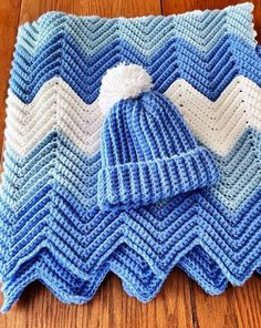 a blue and white blanket with a knitted hat on it sitting on top of a wooden floor