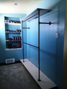 an empty room with shelves and shoes on the floor, in front of a blue wall