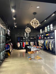 the inside of a clothing store with lots of clothes on racks and lights hanging from the ceiling