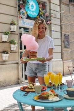 a woman is holding plates with food on them and balloons in the air above her head