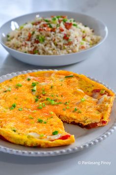 an omelet is on a plate next to a bowl of rice