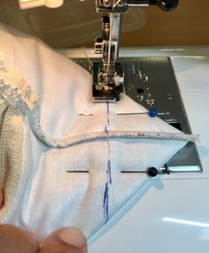 someone is using a sewing machine to sew on the white fabric that has been stitched together