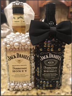 two bottles of jack daniels are sitting on a table next to each other, one with a bow