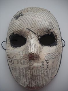 a mask made out of newspaper with black eyes