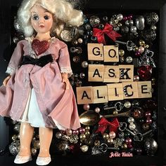 a close up of a doll in front of a sign that says go ask alice