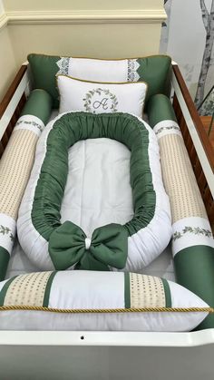 a baby crib with green and white pillows