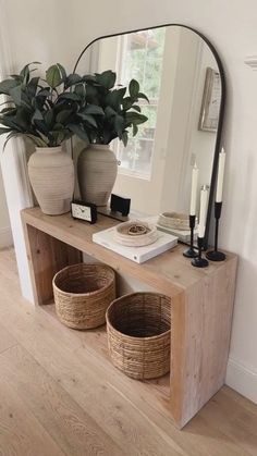 a wooden shelf with two baskets on it and a large mirror in the corner next to it