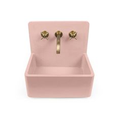 a pink sink with two brass faucets on it