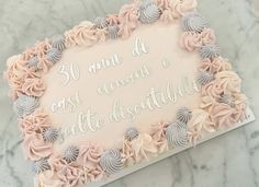 a birthday cake decorated with pink and grey flowers on a marble table top that says 30 anni d'ombre