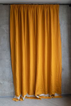 an orange curtain hanging on the side of a wall with concrete walls in the background