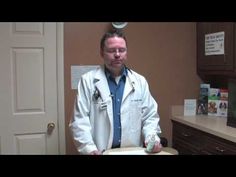 a man in a white lab coat standing next to a table