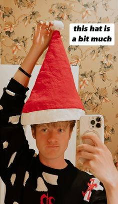 a man wearing a santa hat taking a selfie in front of his cell phone