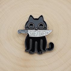 a black and white cat with a knife in its mouth on top of a piece of wood