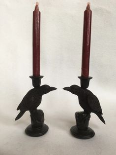 two candles with black birds on them sitting next to each other