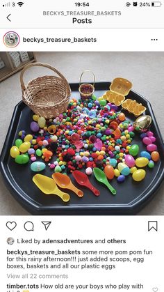 a tray with lots of candy and plastic spoons in it on top of a table