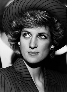 a woman wearing a hat and pinstripe suit looks into the distance with her eyes wide open