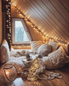 an attic bedroom with lights and pillows on the floor, in front of a window