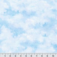 a ruler is next to a blue and white sky with clouds in the back ground