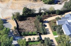 an aerial view of a house surrounded by trees and bushes with lots of dirt on the ground