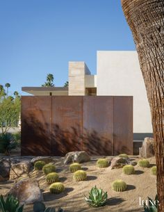 the desert house is surrounded by cactus plants and large concrete blocks, as well as a palm tree