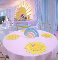 the table is decorated with sun, rainbow and cloud decorations for a birthday party or baby's first birthday